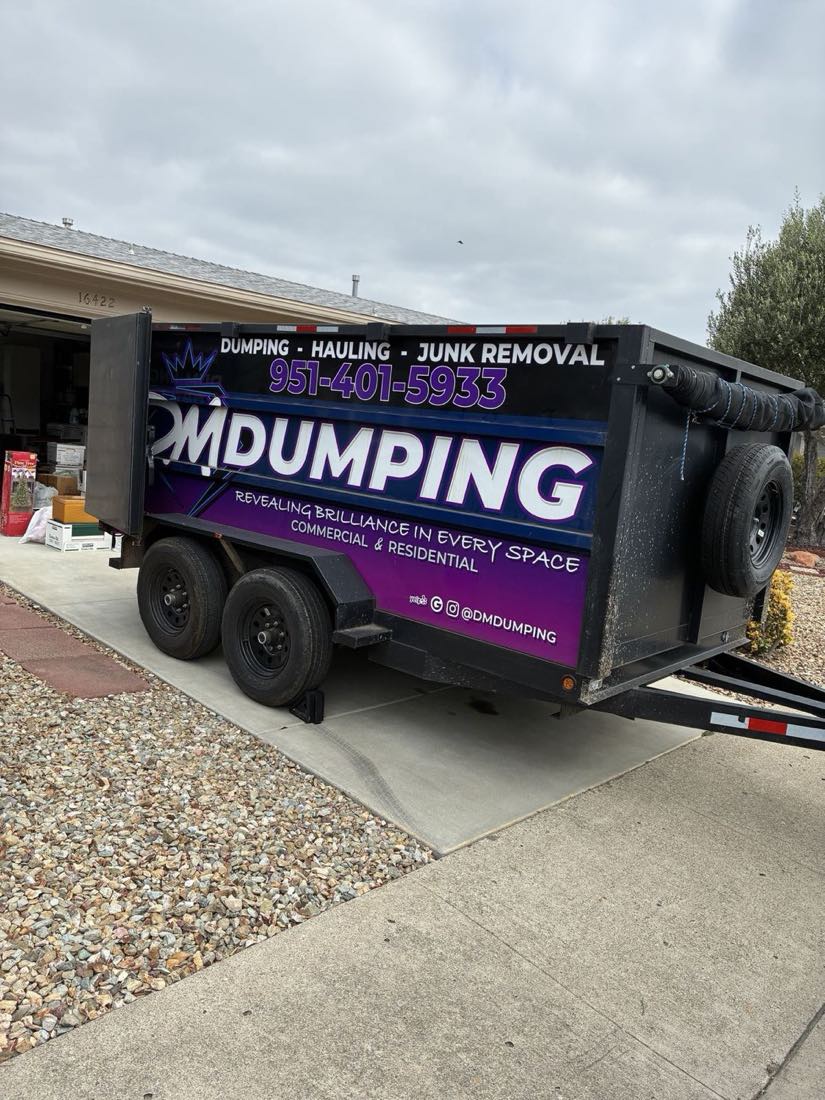 DMD dump trailer parked on a residential driveway during a garage cleanout, phone number 951-401-5933 on the wrap