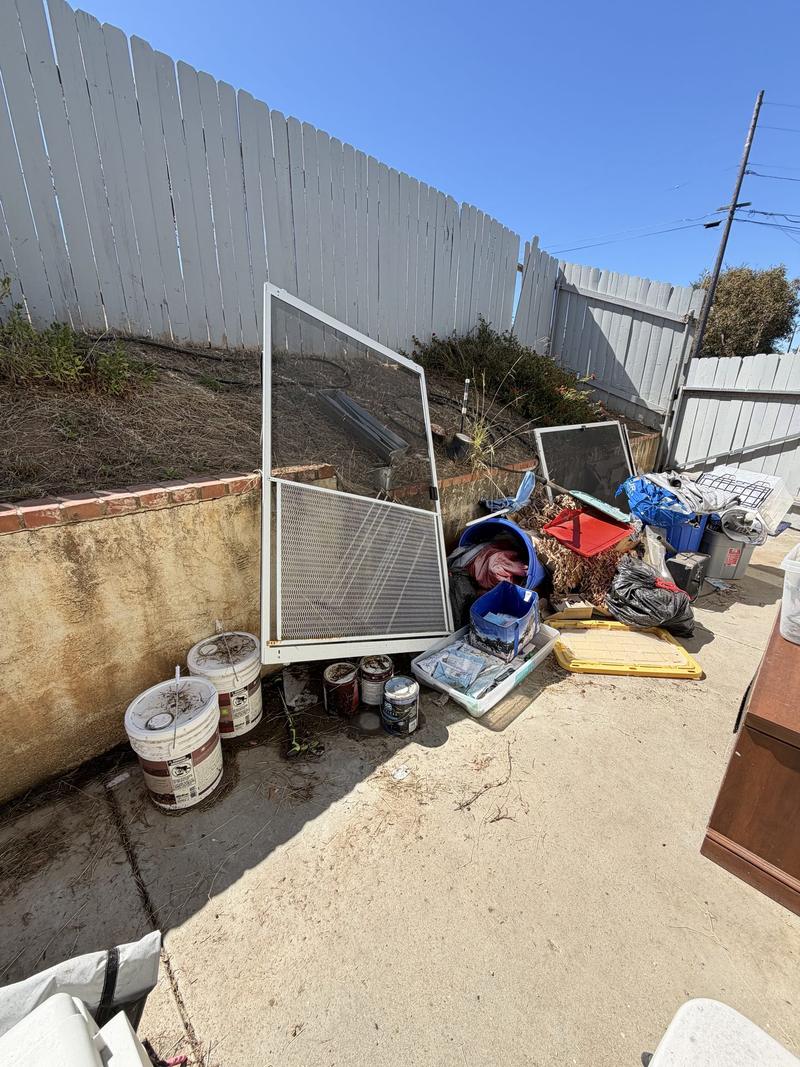 Backyard clearance — old fencing, bins and yard debris staged for pickup