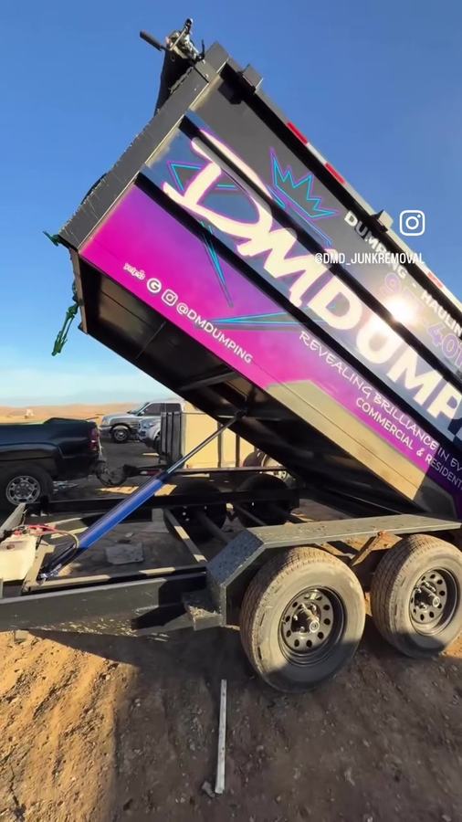 DMD dump trailer raised, unloading a full load at the landfill